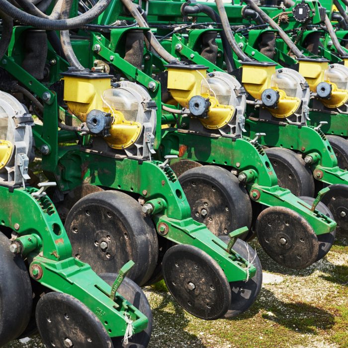 Close up of seeder attached to tractor in field. Agricultural machinery for spring works sowing, seeding
